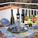 Table set with wine bottles, a tray of glasses, a basket of lemons and decorative tins on a lemon themed tablecloth